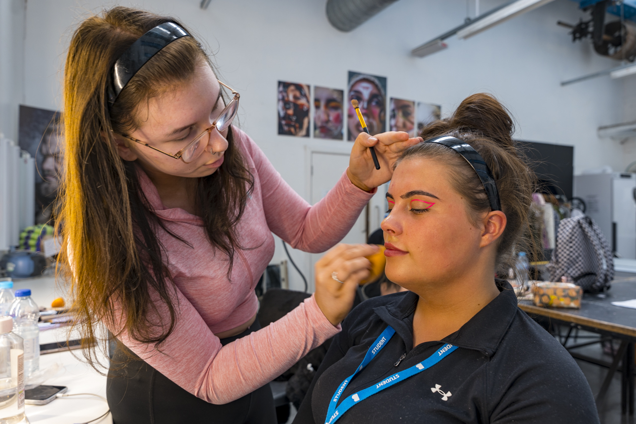 a media make up student applying make up to a student