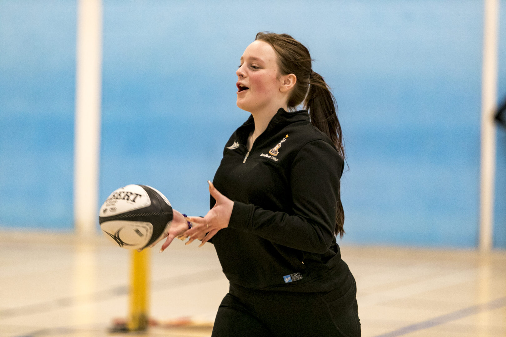 female sports student catching a rugby ball during a practise game of rugby