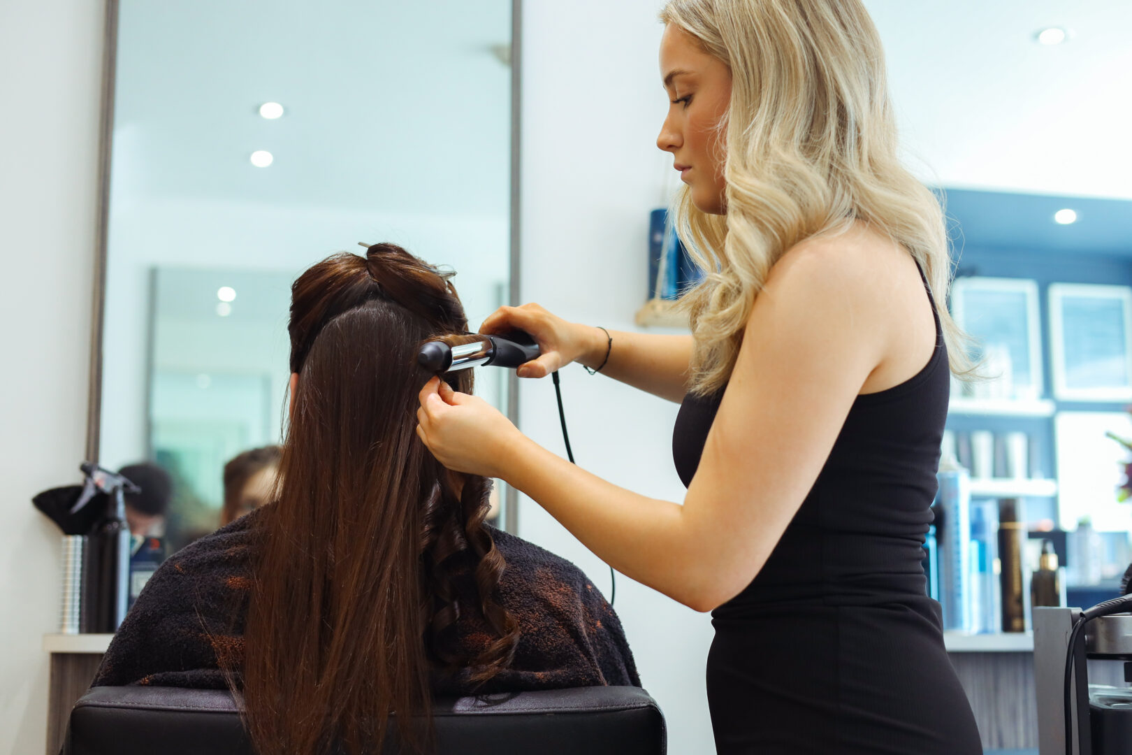 an image of a hairdressing student curling the hair of a model