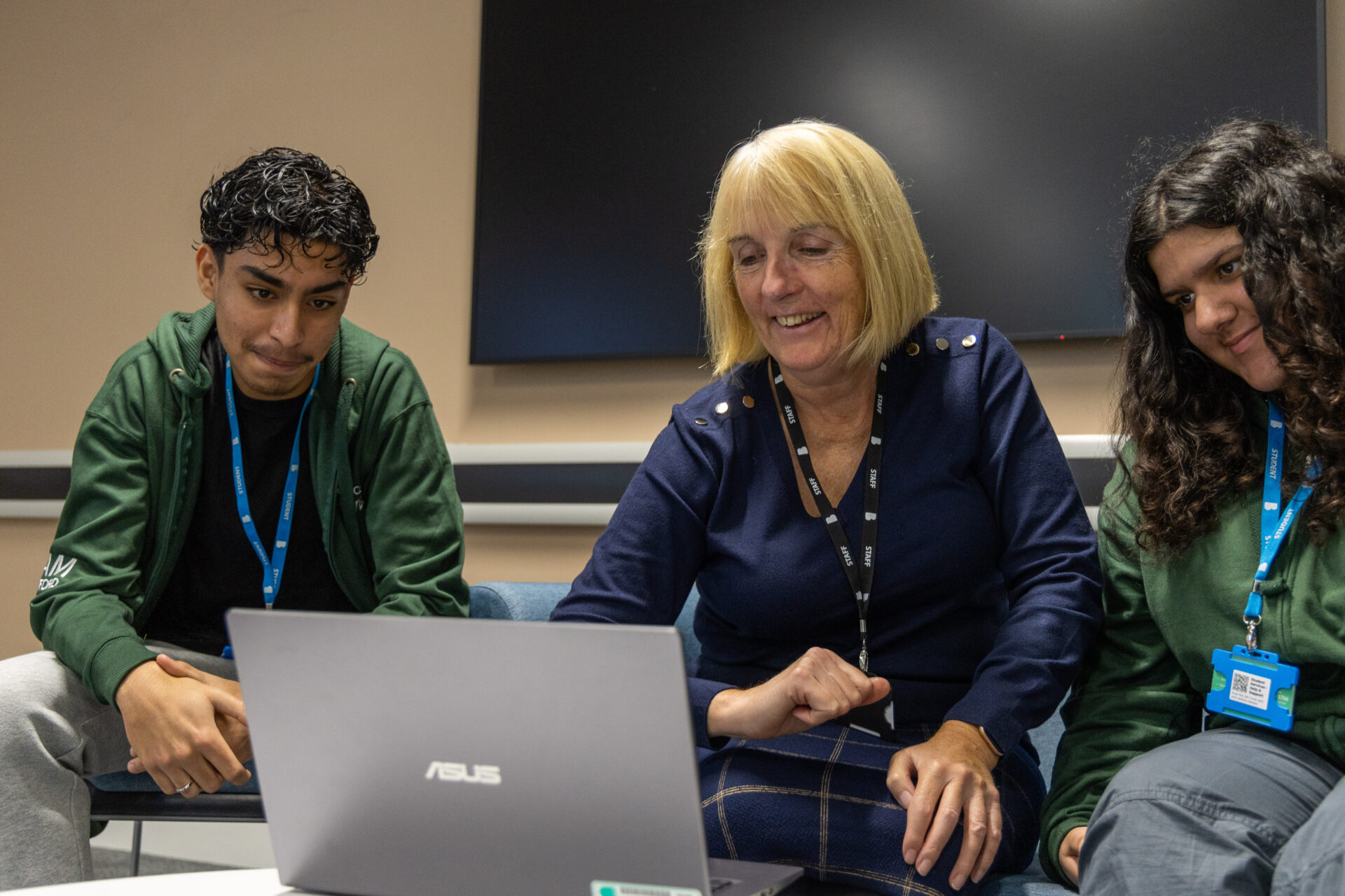 Tutor and students sat together around a laptop in our Business T Level facilities