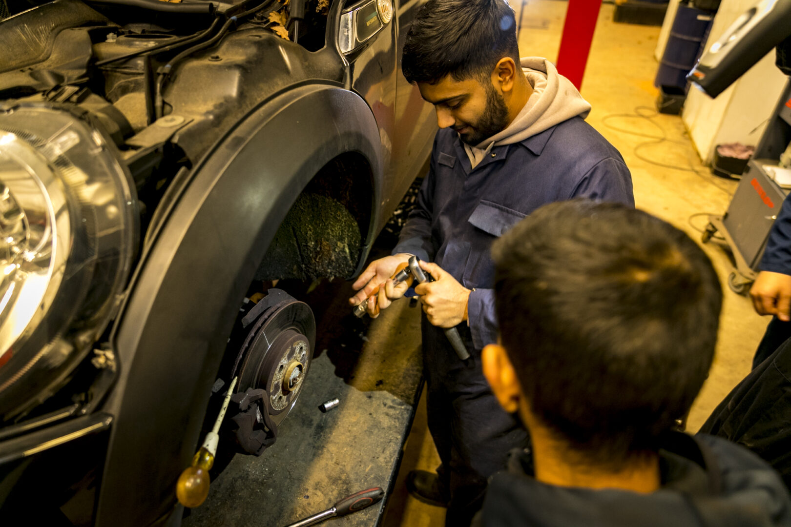 two motor vehicle students working on a vehicle