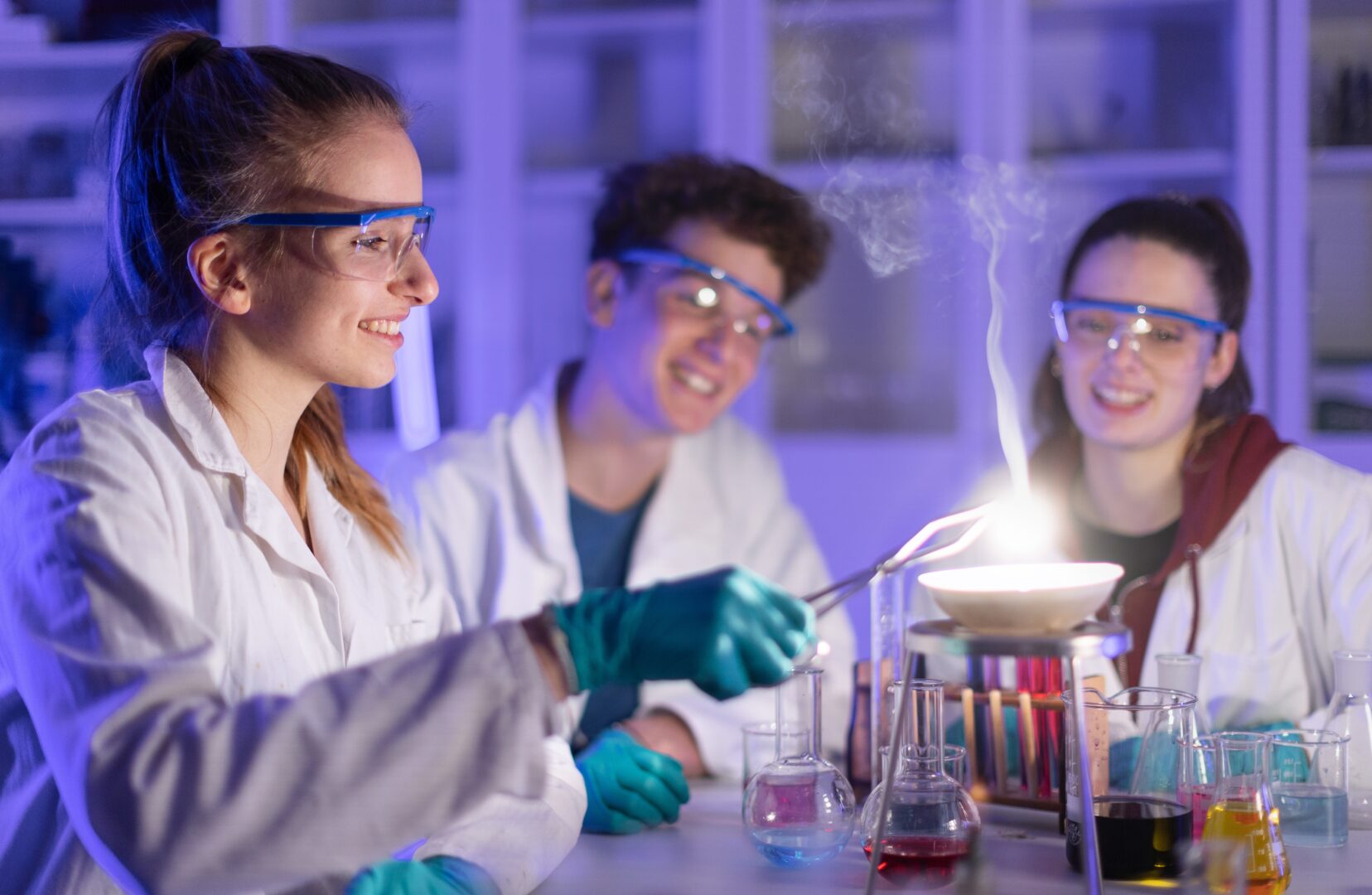 a group of science students all wearing safety glasses and lab coats as they do science experiments