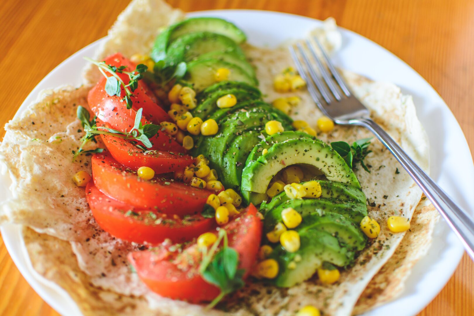 a plate of tomato and avocado arranged in a wrap