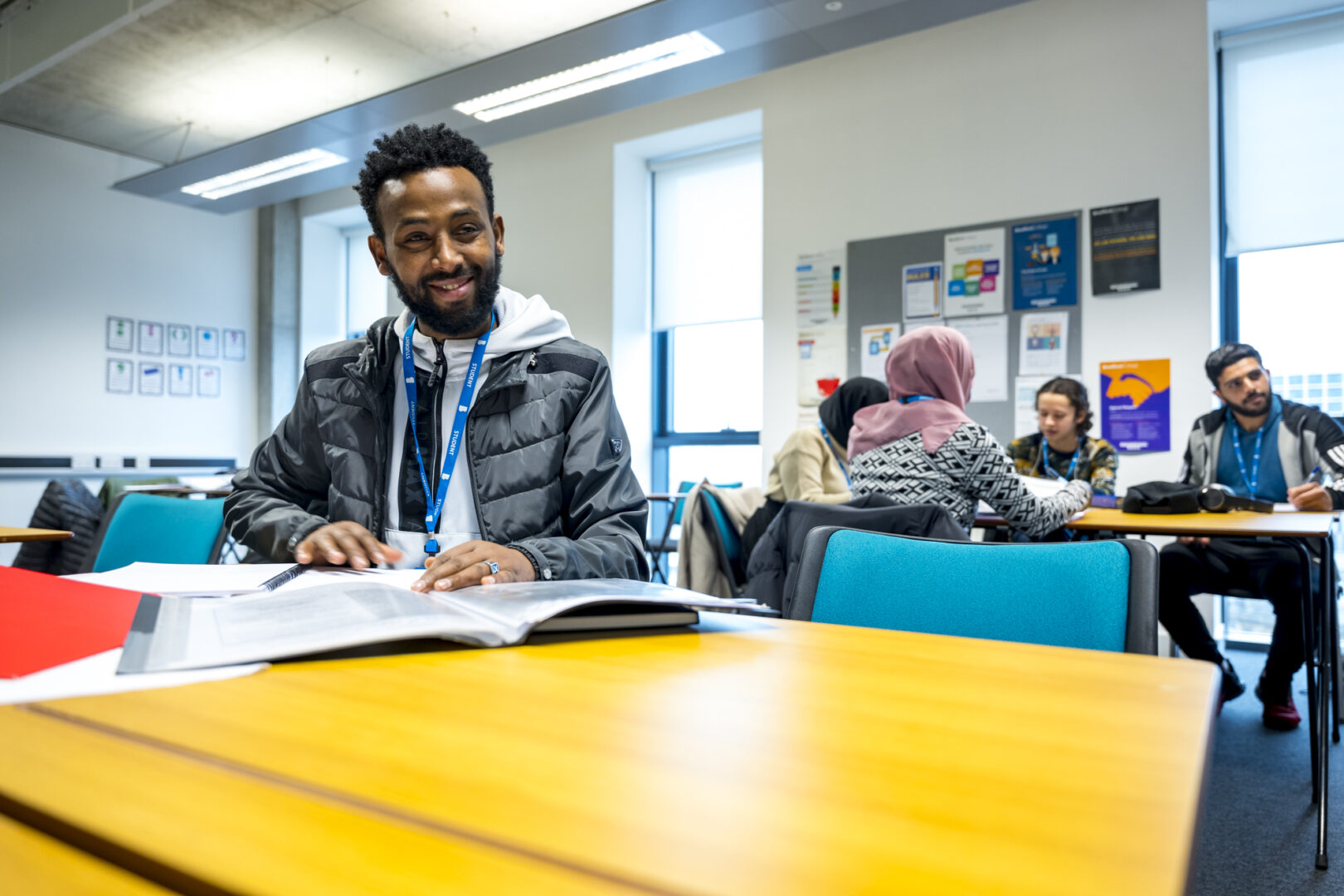 student sat at a desk smiling at the camera