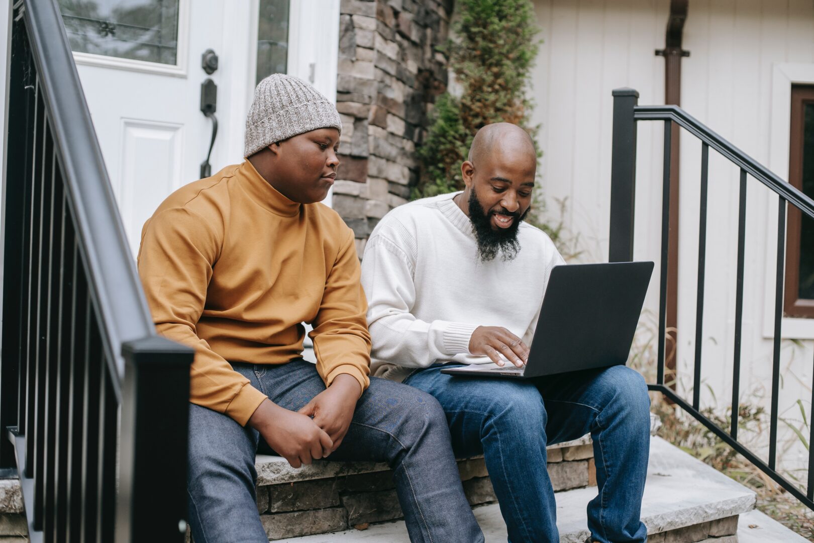 two smiling students sat working at a laptop