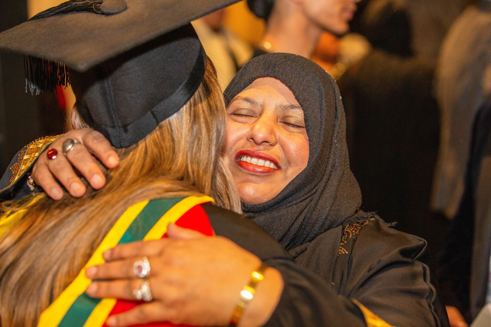 a mother hugs her daughter as she graduates