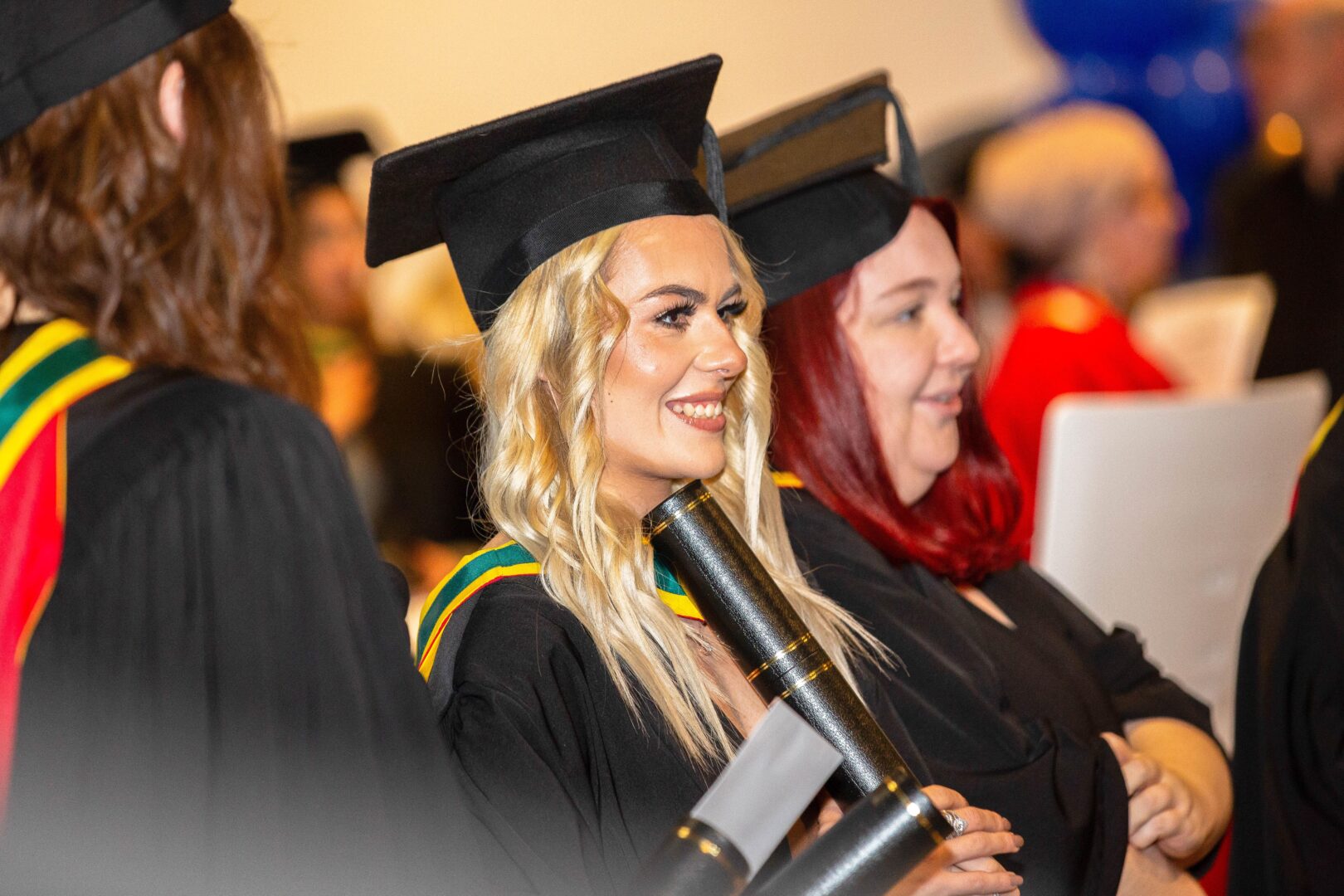 a happy graduate stands looking onwards as she holds her certificate