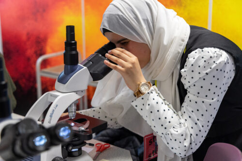 a female student looks into a microscope in our science labratories