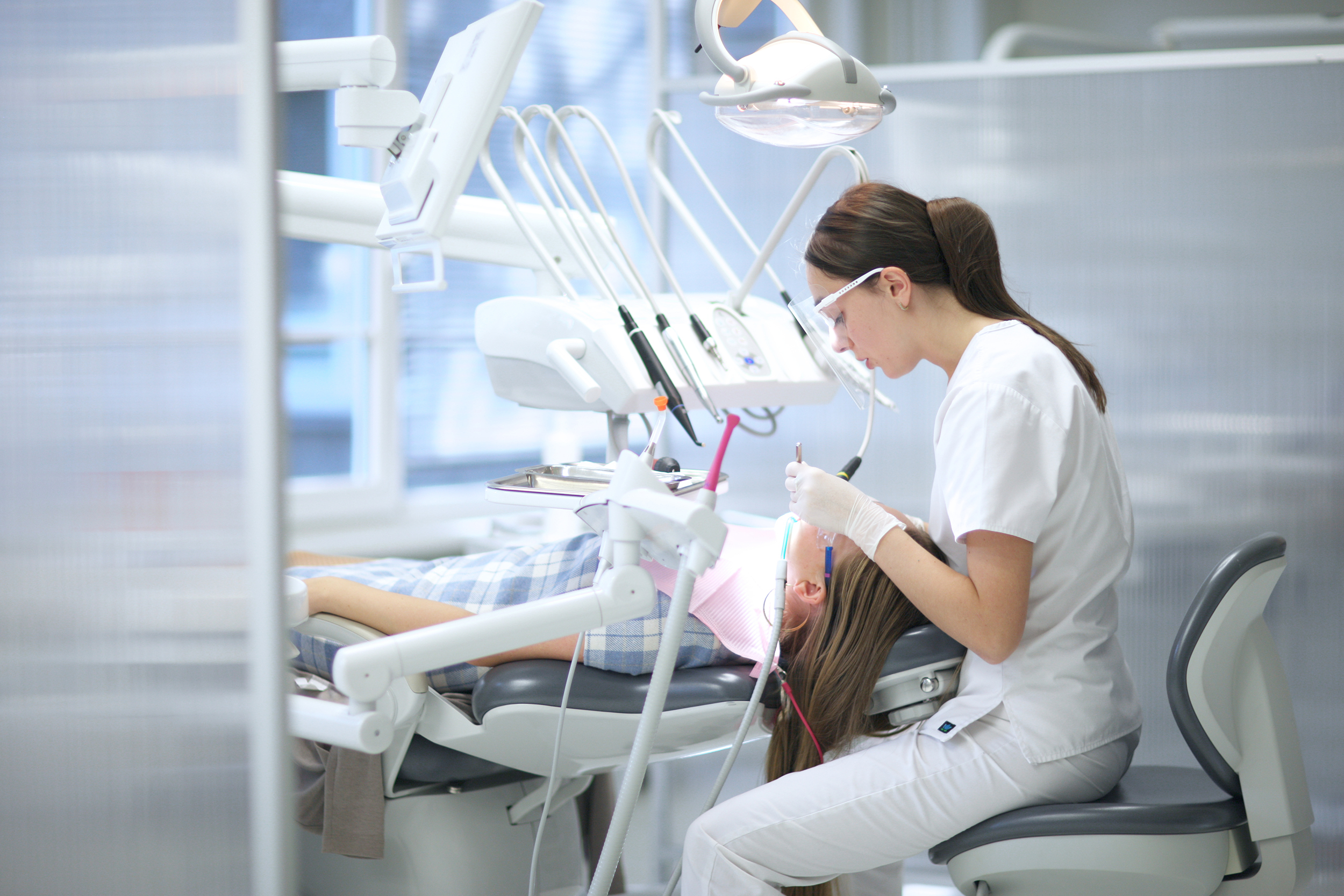 a dental student sits with a patient as she examines their teeth