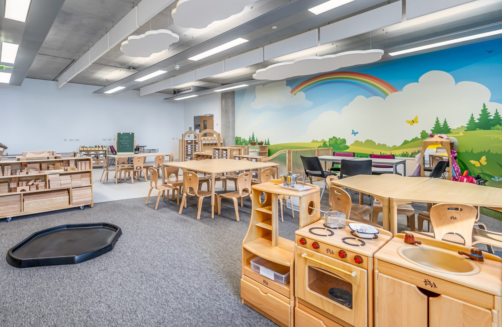 a tlevel early years classroom with bright lights, a colourful wall mural and children's play set