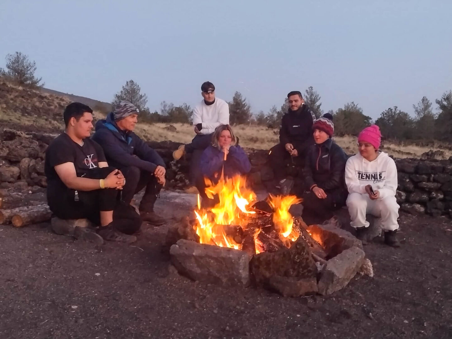 a group of students sit around a camp fire