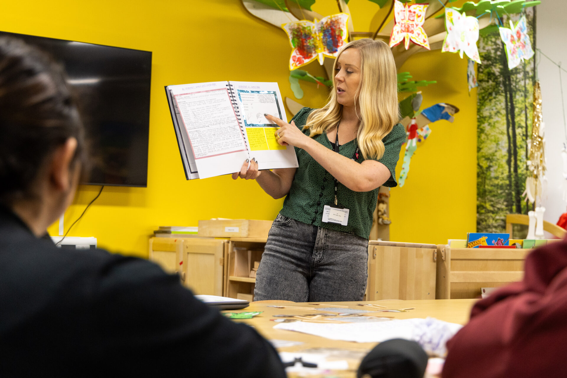 Female tutor teaching from a book in our mock nursery facilities