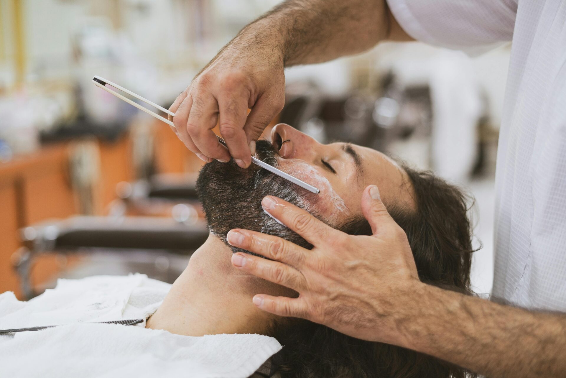 a customer getting their beard cut by a barber