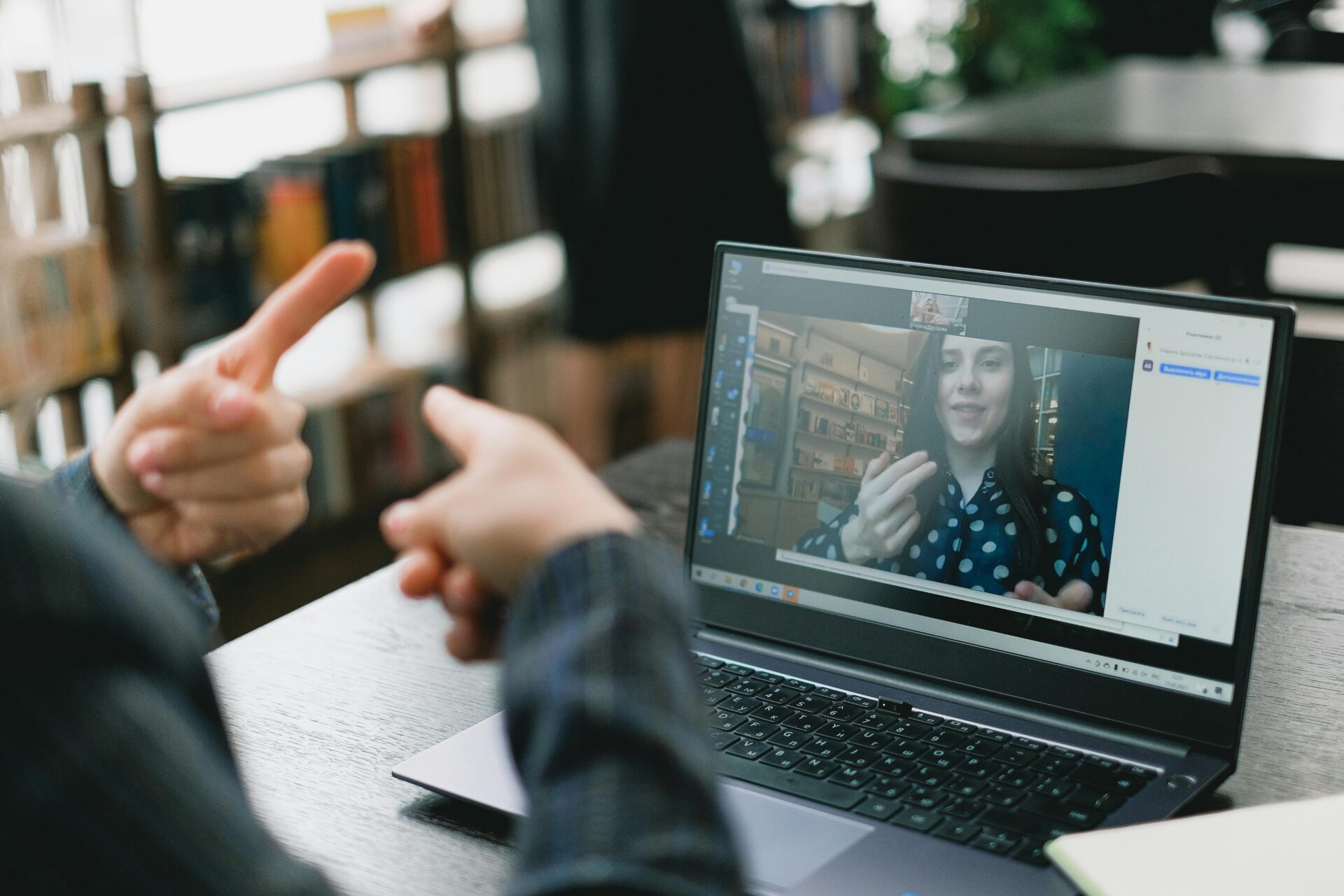 a person sits communicating to another person using sign language over a laptop