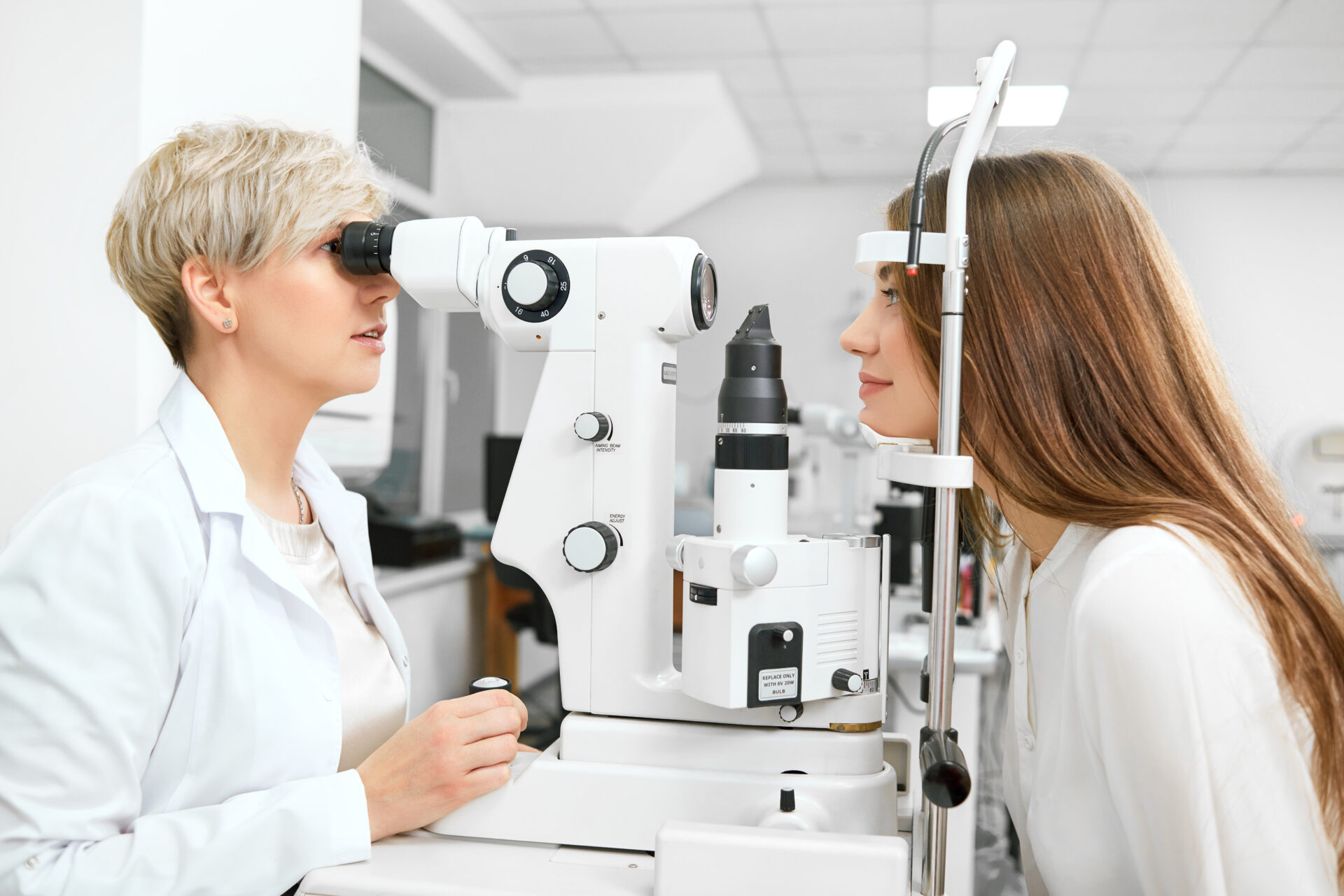 a ophthalmics student looks into a machine as she tests the vision of a patient