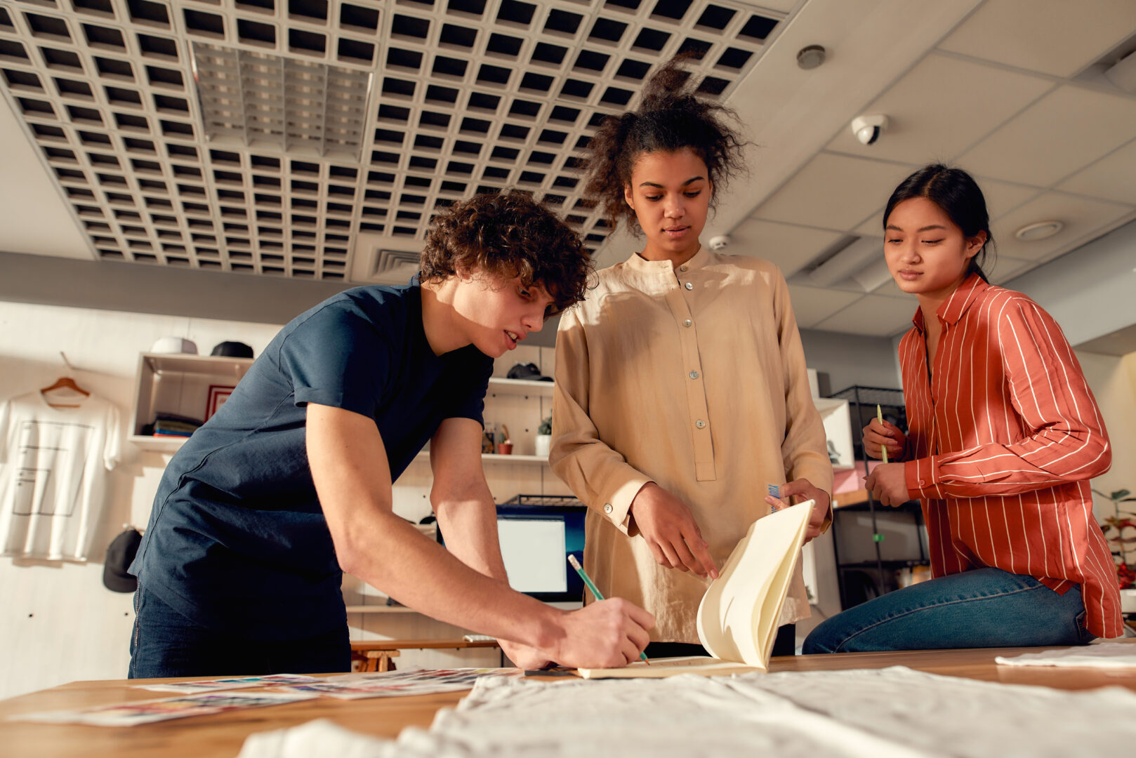 a group of students sit around a desk working on a project