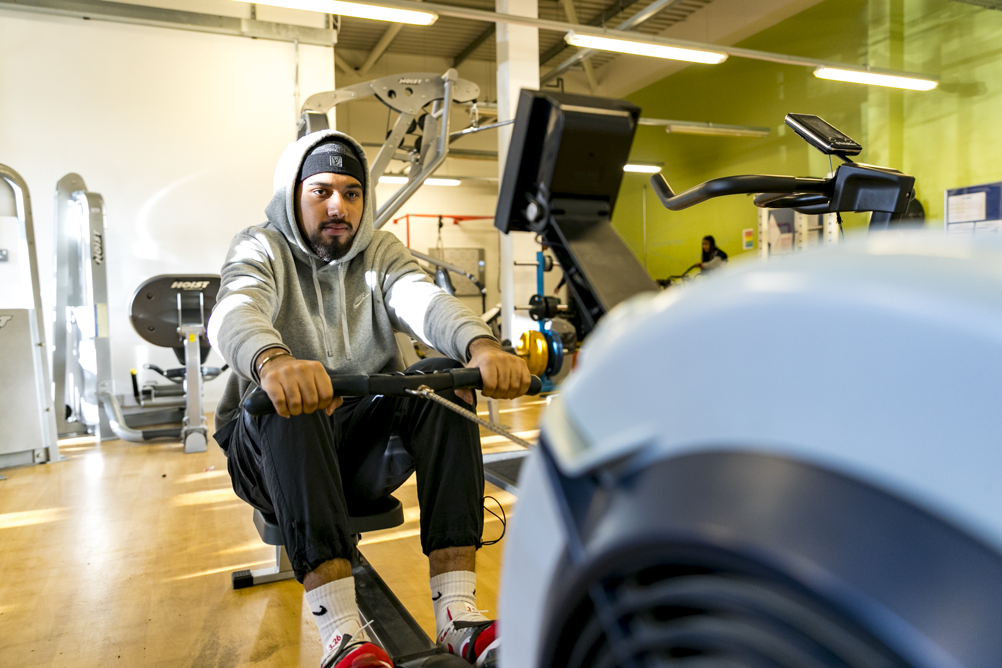 a sports student sits on a rowing machine in a gym