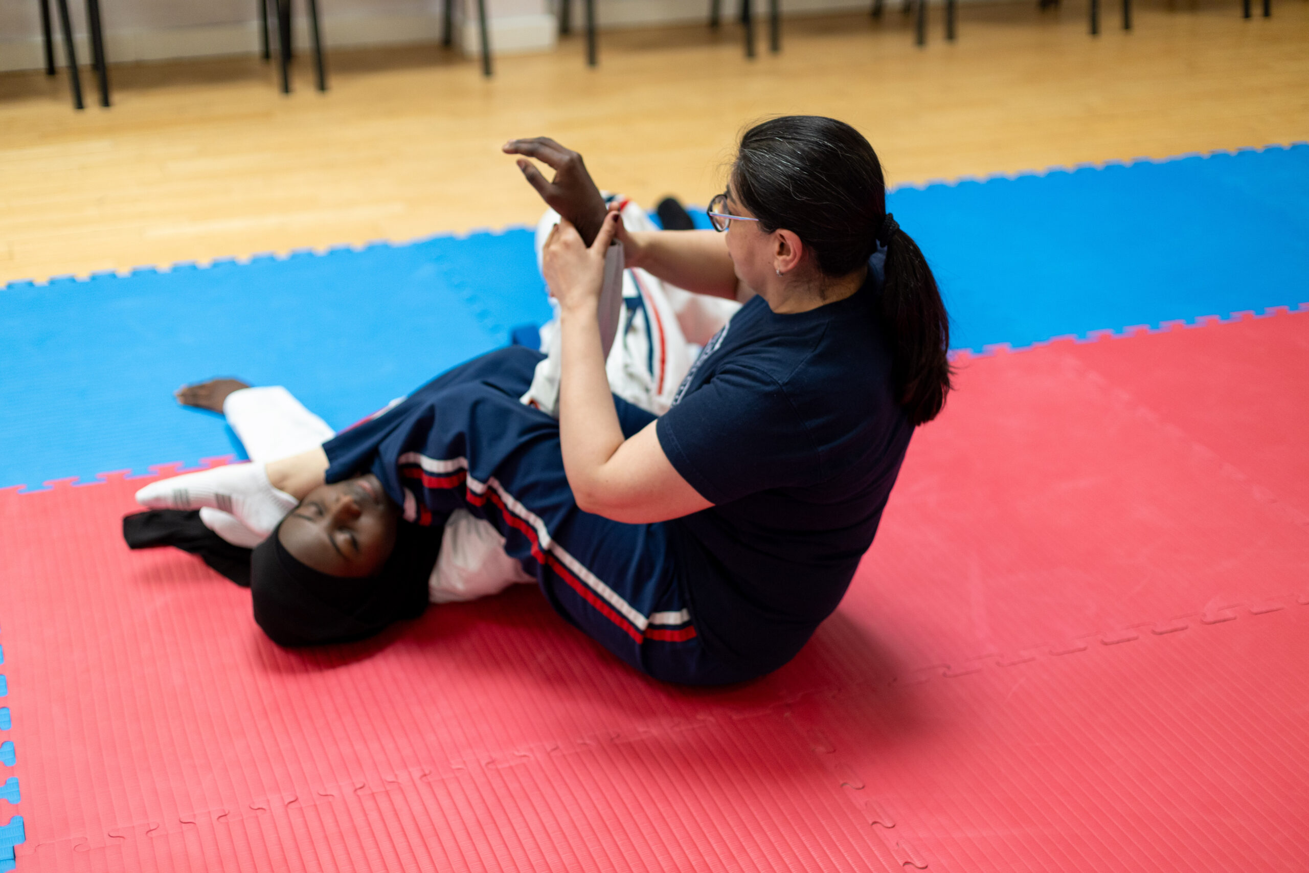 a jiu-jitsu tutor holds a student in a submission pose