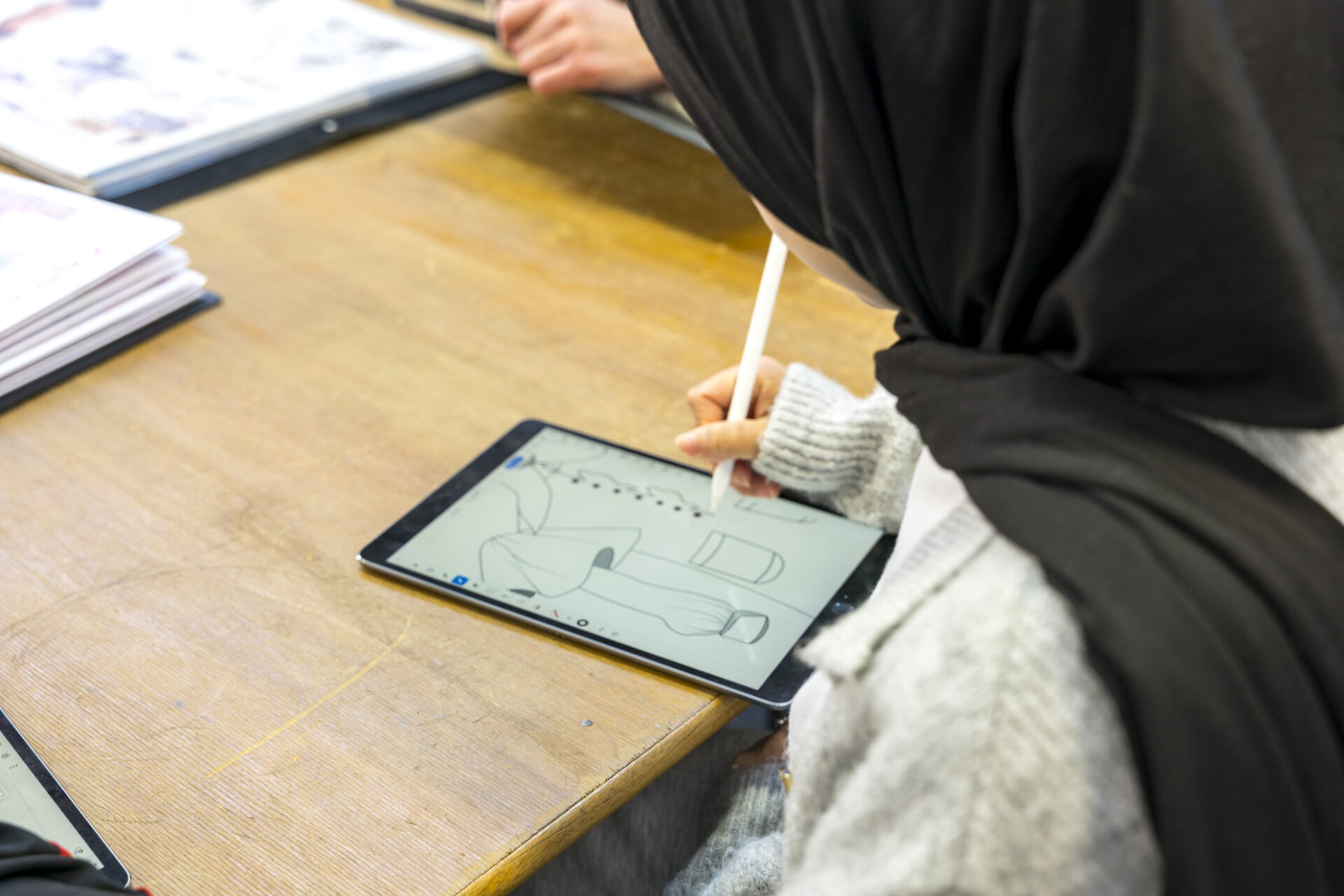 a fashion student uses a tablet to digitally design her work