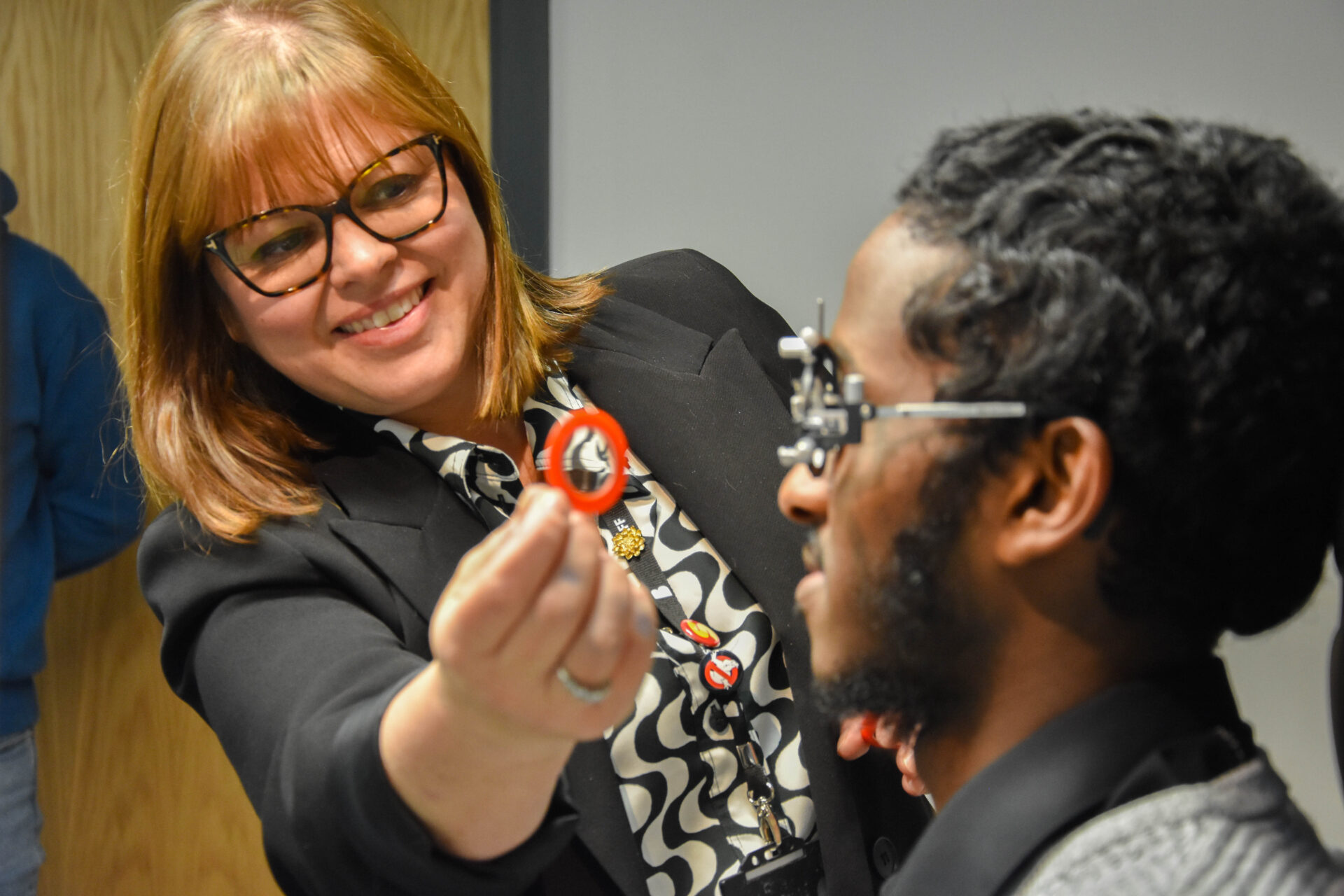 a dispensing optician holds a lens to the eye of a patient