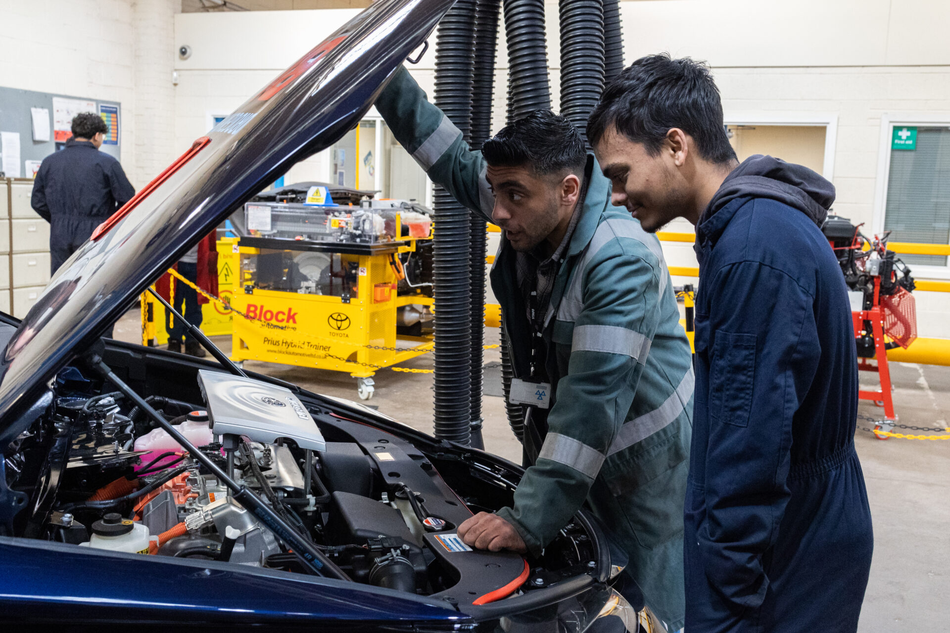 a student and a tutor lift the bonnet of a car and look inside