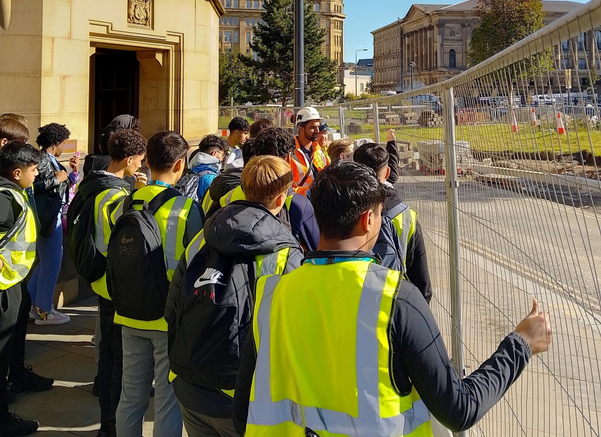 a group of students wearing high vis jackets taking a tour of bradford college