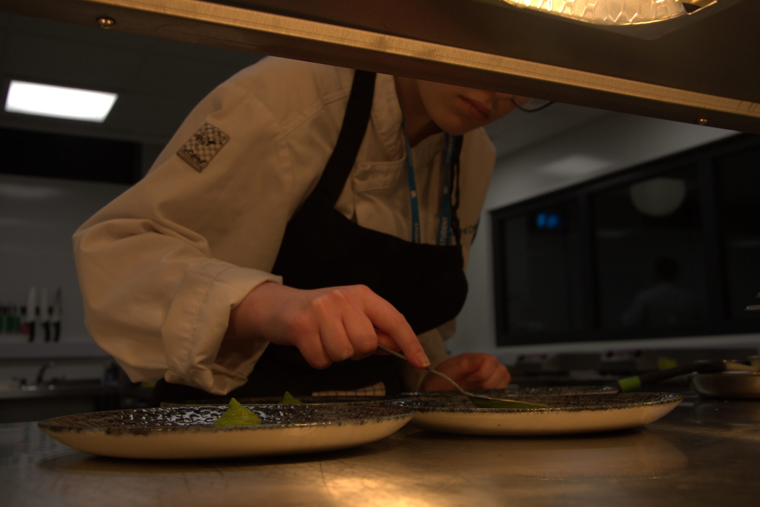 Female student plating up food on the pass in the restaurant