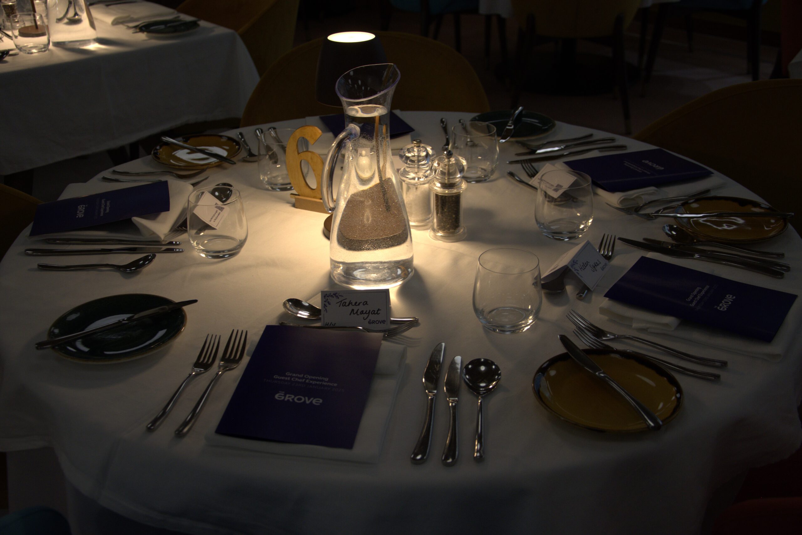 Table with a lamp set up for dinner with cutlery and plates