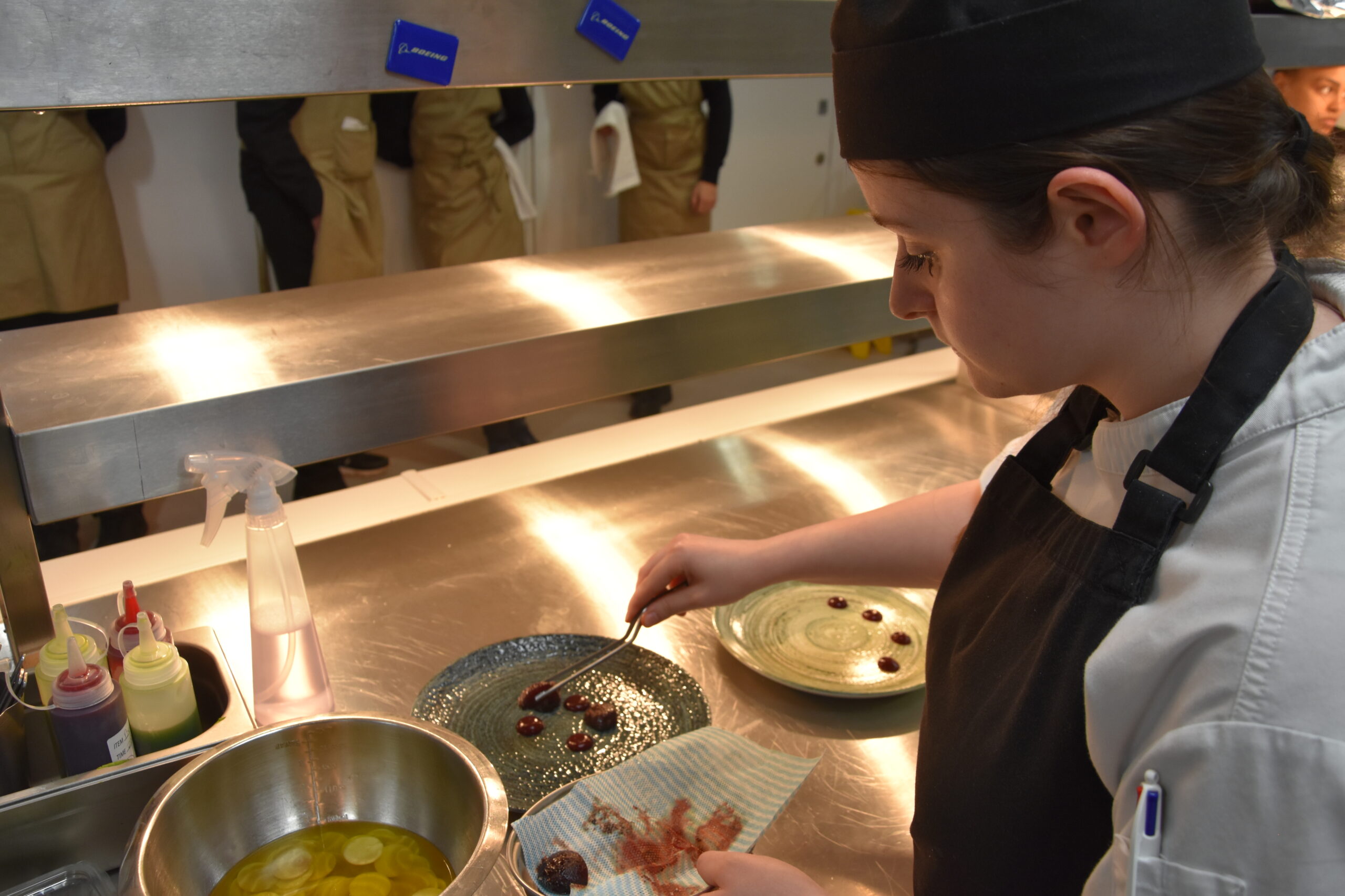 Image of a female student plating up beetroot on the pass in the kitchen